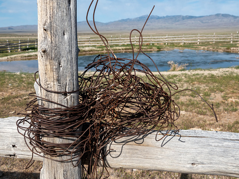Wooden fence post wrapped with bailing wire at an livestock watering pond in the desert.