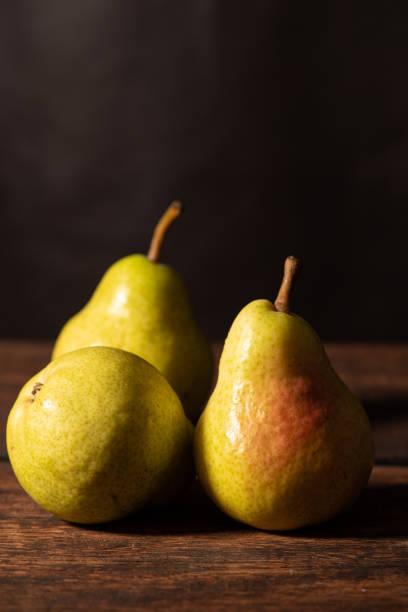 istock Pears, beautiful pears arranged on rustic wood with black background, selective focus. 1493590110