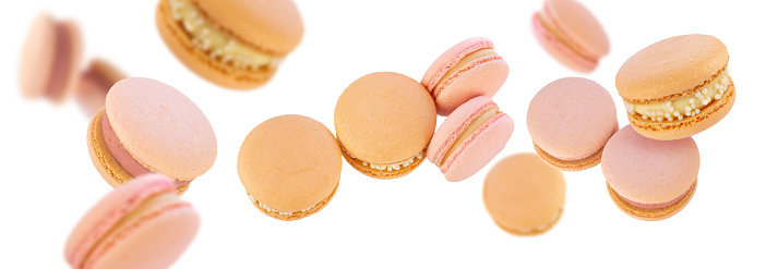 Pink and beige macaroons flying on white background.  French delicate delicious dessert.