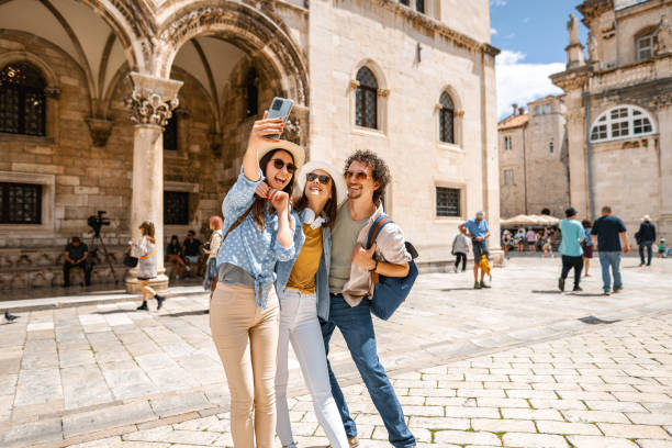 istock Three smiling tourists taking selfies in the old town square 1493594043