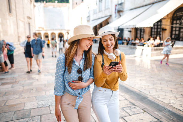 Two young female tourists checking the map while exploring the city