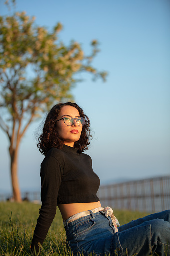 Portrait of young woman in public park during yellow hours.