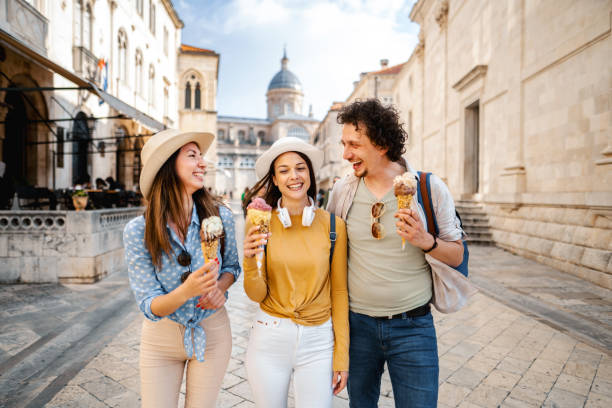 Three smiling tourists eating ice cream while exploring the city