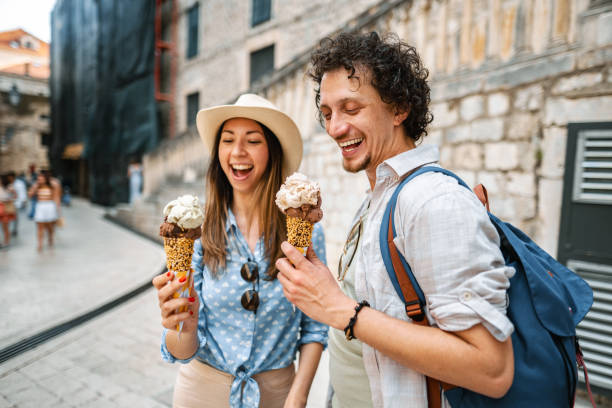 junges touristenpaar, das eis isst, während es die stadt erkundet - people eating walking fun stock-fotos und bilder