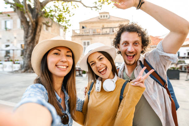 istock Three smiling tourists taking selfies in the old town square 1493596719
