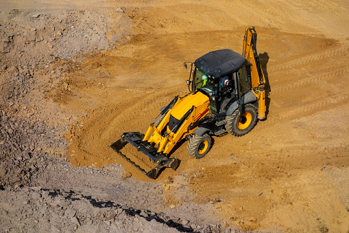 Excavator loading dumper trucks at sunset