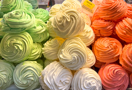 Italian food background: Delicious meringue cookies in Italian flag colors and various tastes.  View from a patisserie window with price label.