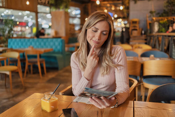 Woman Reading Menu for Ordering in a Coffee Shop