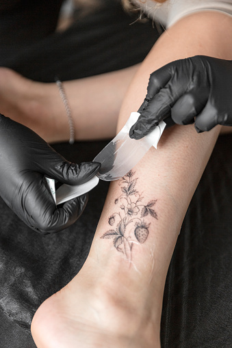 Tattoo master making tattoo on customer's leg