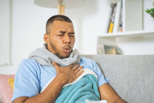 istock Man with asthma, coughing loudly, holding his chest, lying down on the couch 1493631856