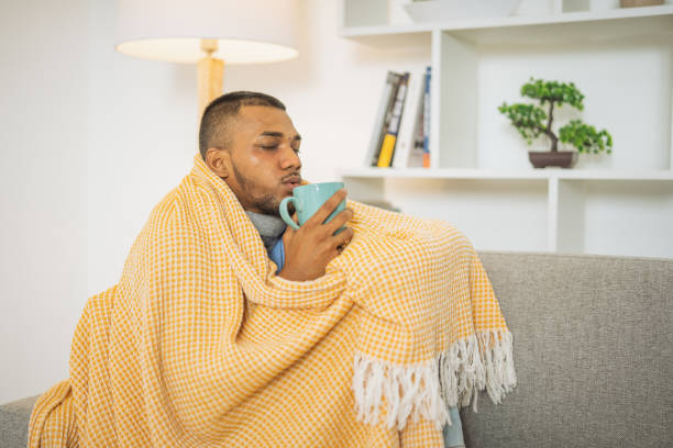 istock Young man with the flu, drinking a cup of tea 1493633252