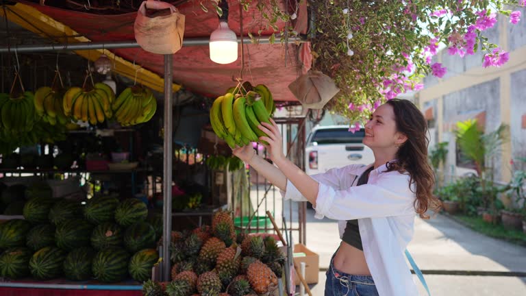 Woman choosing bananas in grocery store in Thailand