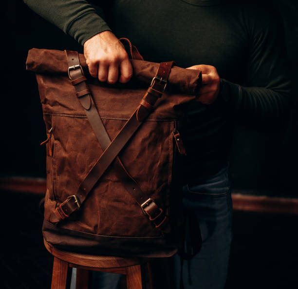 istock man's hand holding a canvas backpack. Model wears a brown belt bag, Medium Leather Backpack Man Rolltop Leather Rucksack Bag 1493644554