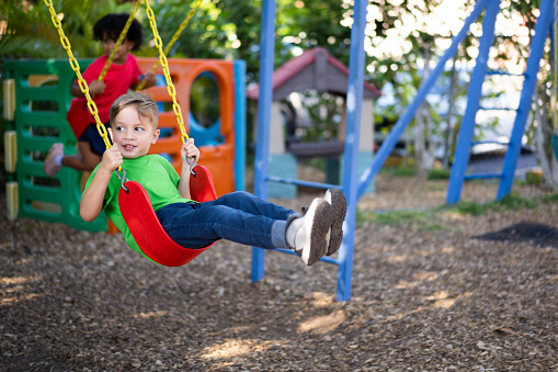 Cheerful boy having fun as he swing on the playground