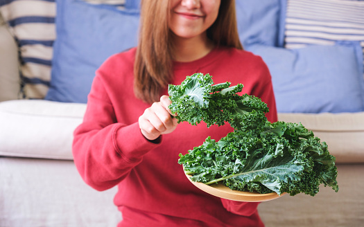 Closeup image of a young woman holding and picking up kale leaves