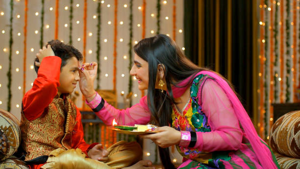 Happy brother sister celebrating Raksha Bandhan on Bhai Dooj festival - Indian Model On the festival of Raksha Bandhan/Bhai Dooj, beautiful elder sister putting tika on her brother's forehead - happy moment bhai tika stock pictures, royalty-free photos & images