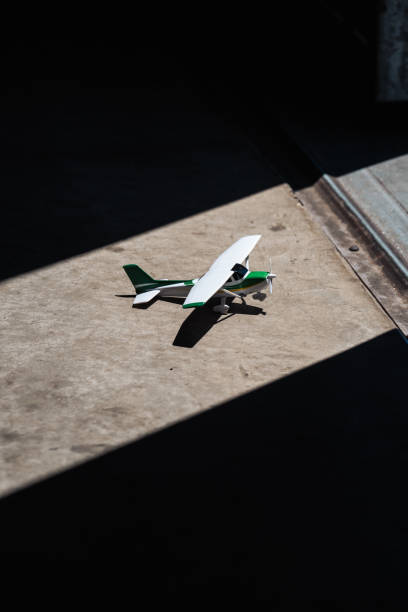 A model airplane is parked inside the hangar, basking in the sunlight that streams down upon it, accentuating its intricate features and casting a radiant glow.