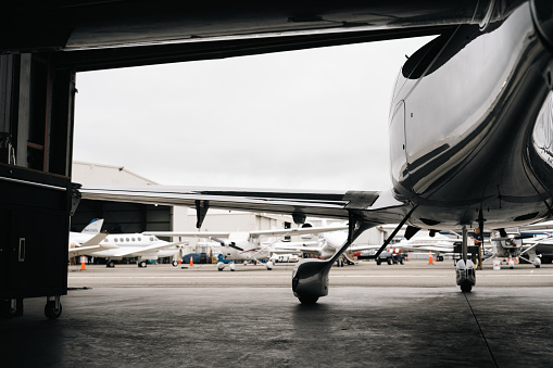 Parked inside the hangar, an aircraft provides a vantage point to observe the scenery outside, offering a glimpse of the surroundings beyond the hangar doors.