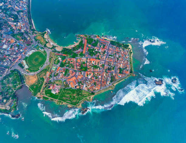 Captivating Aerial View of Galle Fort: A Historic Gem Amidst Coastal Beauty Galle Fort is a UNESCO World Heritage Site located in Galle, Sri Lanka. Originally built by the Portuguese and fortified by the Dutch, it features well-preserved colonial-era buildings, including Dutch-style villas, churches, and mosques. The fort's architecture combines European and South Asian influences, and its narrow streets are now home to boutique hotels, restaurants, and shops. With its panoramic views, historical sites, and proximity to stunning beaches, Galle Fort offers a captivating blend of history, culture, and natural beauty. southern sri lanka stock pictures, royalty-free photos & images