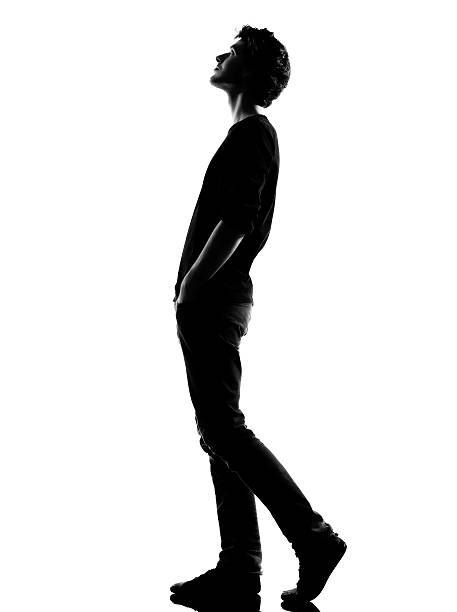young man silhouette walking looking up young man  walking looking up silhouette in studio  on white background back lit stock pictures, royalty-free photos & images