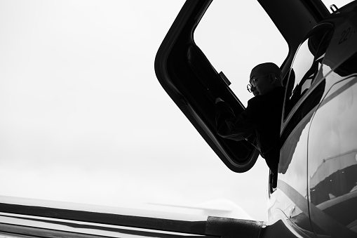 A pilot sits in the cockpit, raising the cabin door to reveal a mysterious silhouette.