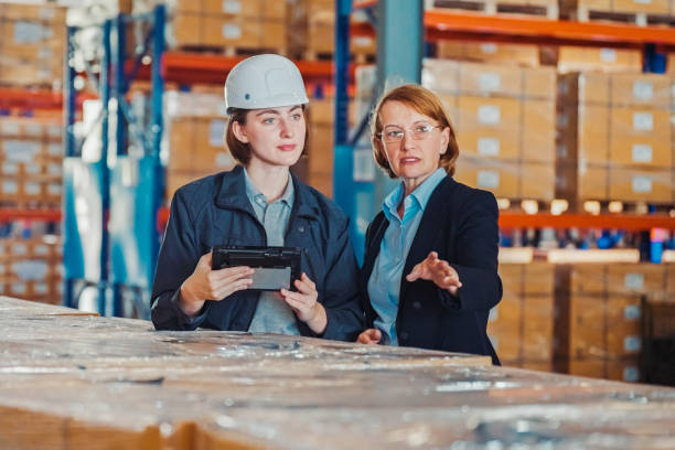 Businesswoman manager discuss with warehouse worker  in a distribution warehouse