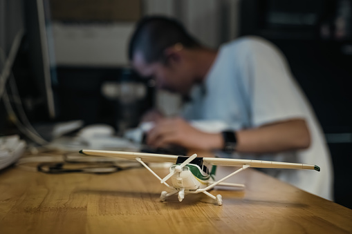 A young pilot student diligently works on his test, with a model airplane resting beside his textbooks, serving as a source of inspiration and motivation.