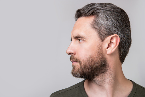 profile portrait of caucasian guy with stubble isolated on grey background. caucasian guy with stubble in studio. photo of caucasian guy with stubble. caucasian guy with stubble wear tshirt.