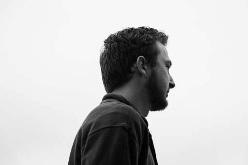 A monochromatic profile portrait of a young man, capturing his side profile with a timeless elegance and a touch of mystery.