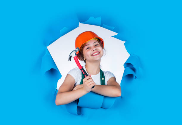 istock Child care development. Kid engineer with carpenter work hammer. Labor day at 1 may. little girl in hard hat holds hammer. best repairer ever. learning to use hammer. hammering. she is good assistant 1493683552