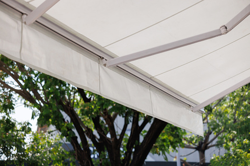 white awning with garden background. white canvas roof of the store.