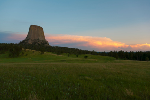 Devils Tower at dusk with thunder clouds moving over the horizon.