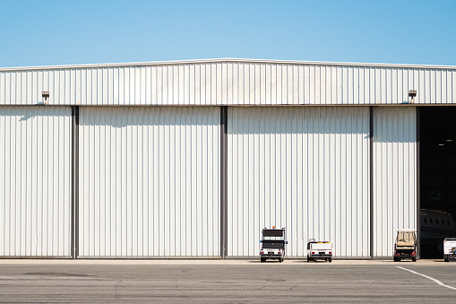 In front of a massive hangar, several golf carts are parked, ready to transport personnel and equipment within the expansive facility.