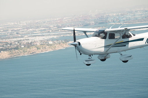 An airplane flying, soaring towards the boundless horizon with cityscape in the background