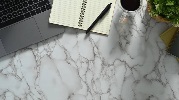 istock Feminine workspace with laptop, notepad and coffee cup on marble table. Top view with copy space. 1493690502