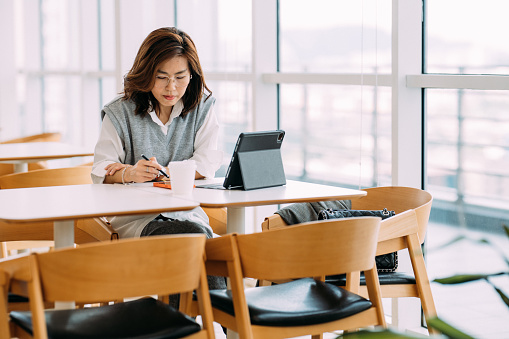 Beautiful Asian business woman using her laptop designing creative ideas and planning on her project at Co-working Space.