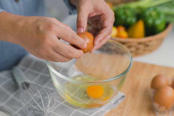 jeune femme cuisinant dans une cuisine lumineuse, des jaunes d’œufs frais concassés faits à la main dégoulinant dans le bol. préparer des ingrédients pour une cuisine saine. nourriture faite maison - break eggs domestic kitchen breaking photos et images de collection