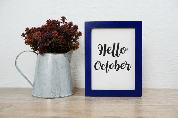 istock Hello October typography text with artificial plant decoration on wooden table and white wall background 1493696975
