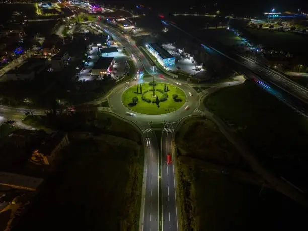 Aerial view of a bustling city street and highway intersection illuminated by bright lights at night