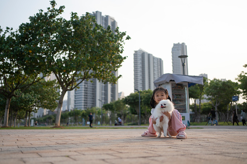 Cute little Asian girl playing with her pet dog outdoor