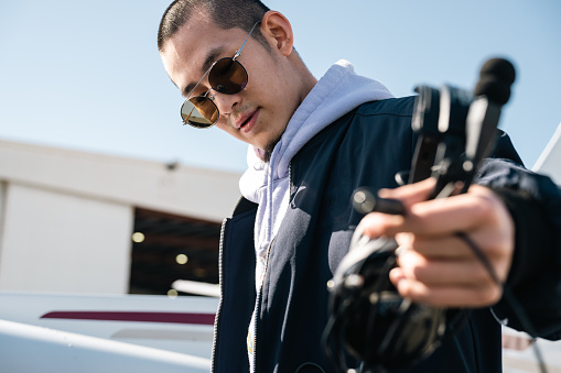 An young pilot holds his noise-canceling headphones, a trusted companion during his flights.