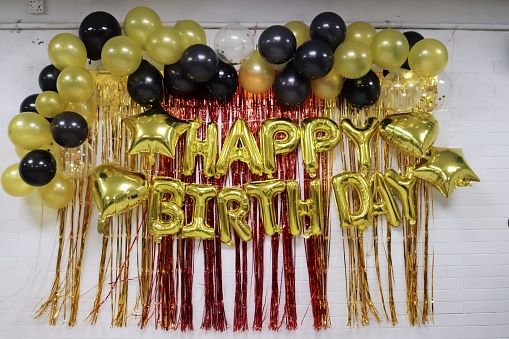 A wall decorated by - happy birthday letters,balloons, and other instruments.