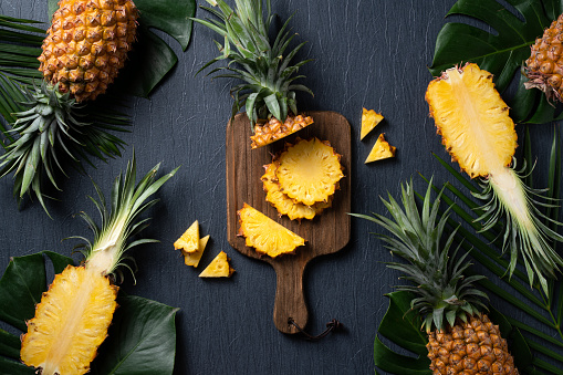 Cut and whole ripe pineapples on wooden table, flat lay. Space for text