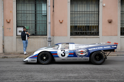 Cernobbio, Como - May 21, 2023: Concorso d'Eleganza Villa d'Este 2023.\nA 1971 Porsche\n917K\nTech Specs\nEngine Flat-twelve air-cooled engine, mounted midship, twin overhead camshafts, fuel-injected. 4907cc, 600hp.\nDrives through on the public road on Via Regina Cernobbio.\n\nIn Europe, the Concorso d'Eleganza Villa d'Este has developed into a meeting point for lovers of high-quality classic automobiles.\nActive automotive designers are also looking for inspiration for their work there.\nIn addition, the event is given a special touch by the Villa d'Este, a former cardinal's palace with park, located directly on the lake\na neat setting and a social touch.\nOn Sunday, vehicles for the general public will be shown on the grounds of the neighboring Villa Erba.\nThe vehicles drive early in the morning from Villa d'Este to Villa Erba through the small town of Cernobbio\nat Como\non the public road, on Via Regina\n\nIn the background you can see the church Chiesa di Maria delle Grazie.\n\n\n\nThe event traditionally takes place on the third weekend in May each year.\n\nA jury decides on the two prizes \