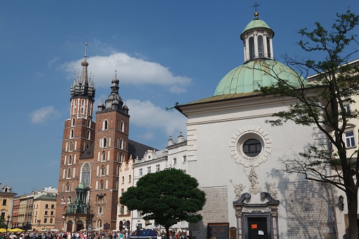 Krakow, Poland – June 16, 2013: People walking in main square in Krakow, Poland, with buildings in the background