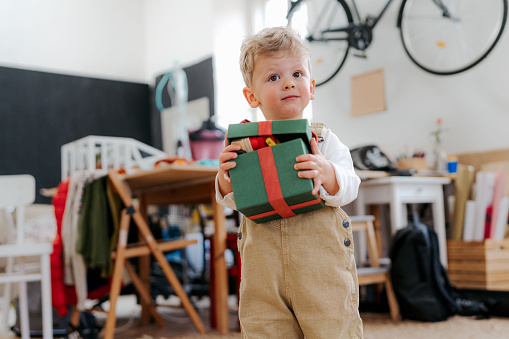 Surprised little boy getting a present. Happy child holding and opening gift box.