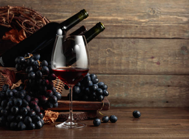 vin rouge et raisins bleus sur une vieille table en bois. - merlot cabernet photos et images de collection