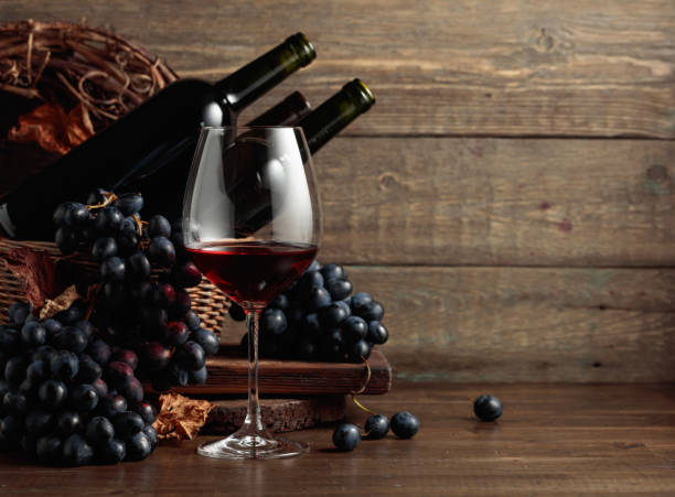 Red wine and blue grapes on an old wooden table. stock photo