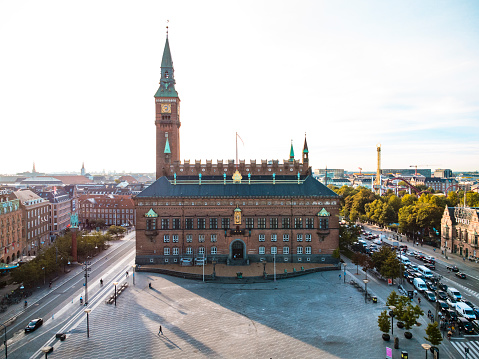 Aerial drone image of the Copenhagen City Hall with its impressive tower and watch, shot at twilight. Cityscape with contemporary office buildings and residential flats in central Copenhagen.