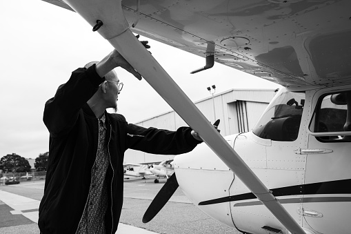 A young man is seen towing his light aircraft with his hands firmly grip the bar under the wing.